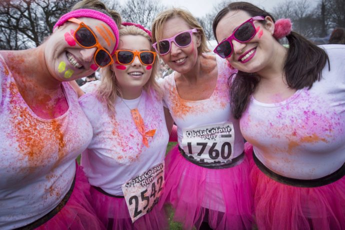 Ladies in pink tutus covered in paint at ObstaColour Run