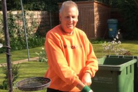 Derek in his garden wearing gardening gloves.