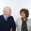 Ian and Janice together with their arms linked together, looking at eachother and smiling.