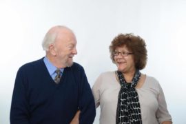 Ian and Janice together with their arms linked together, looking at eachother and smiling.