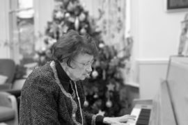 A black and white photo of Frances playing the piano at Christmas