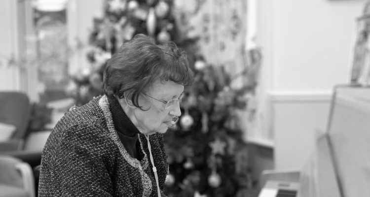 A black and white photo of Frances playing the piano at Christmas