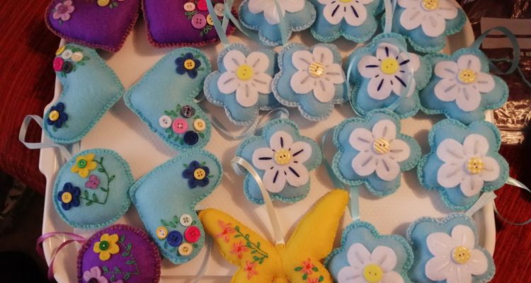 A selection of hanging felt flowers, hearts and butterflies in light blues, yellows and purple colours.