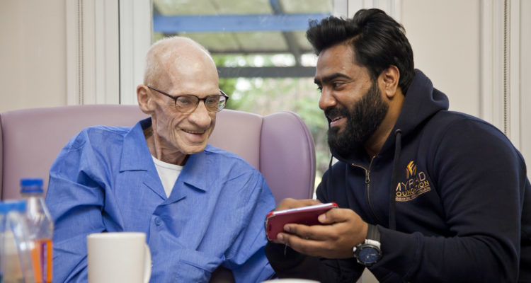 A member of The Myriad Foundation sits with an inpatient at St Ann's.