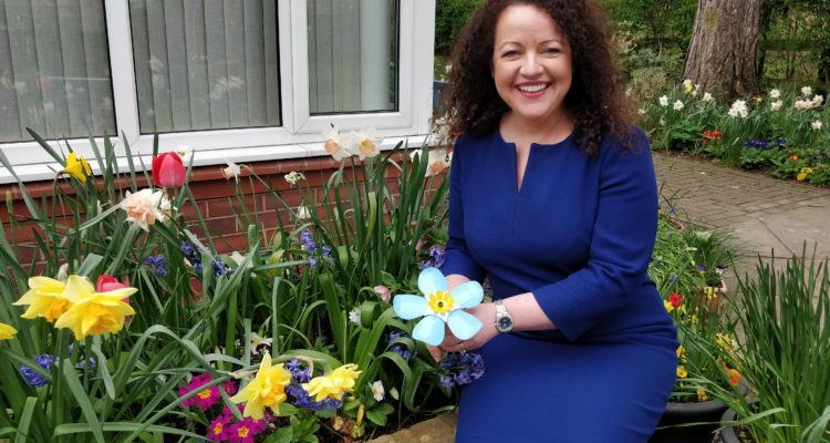 Rachel McMillan sat in the hospice gardenholding a metal forget-me-not
