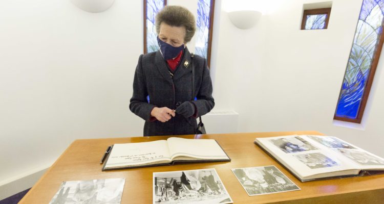 The Princess Royal signs a visitors book.